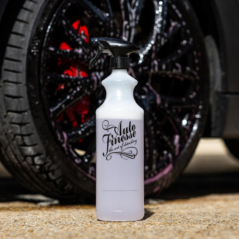 Spray bottle labeled 'Auto Finesse' in front of a car wheel