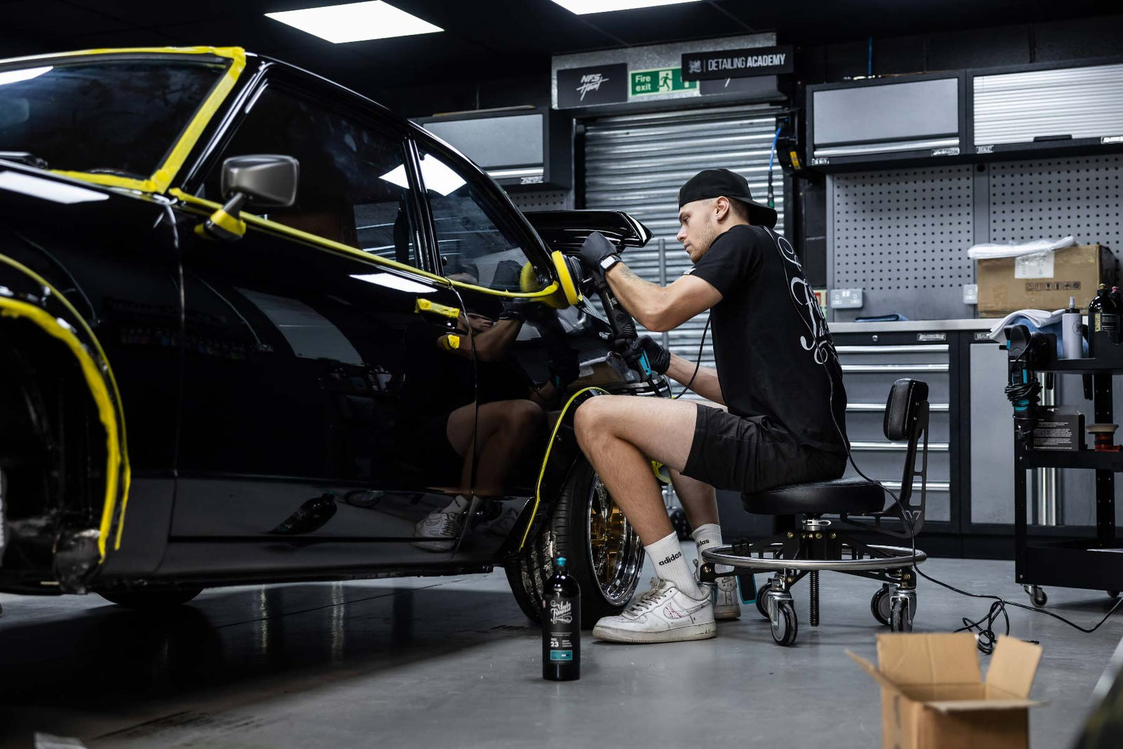 Detailer machine polishing a car in  a garage