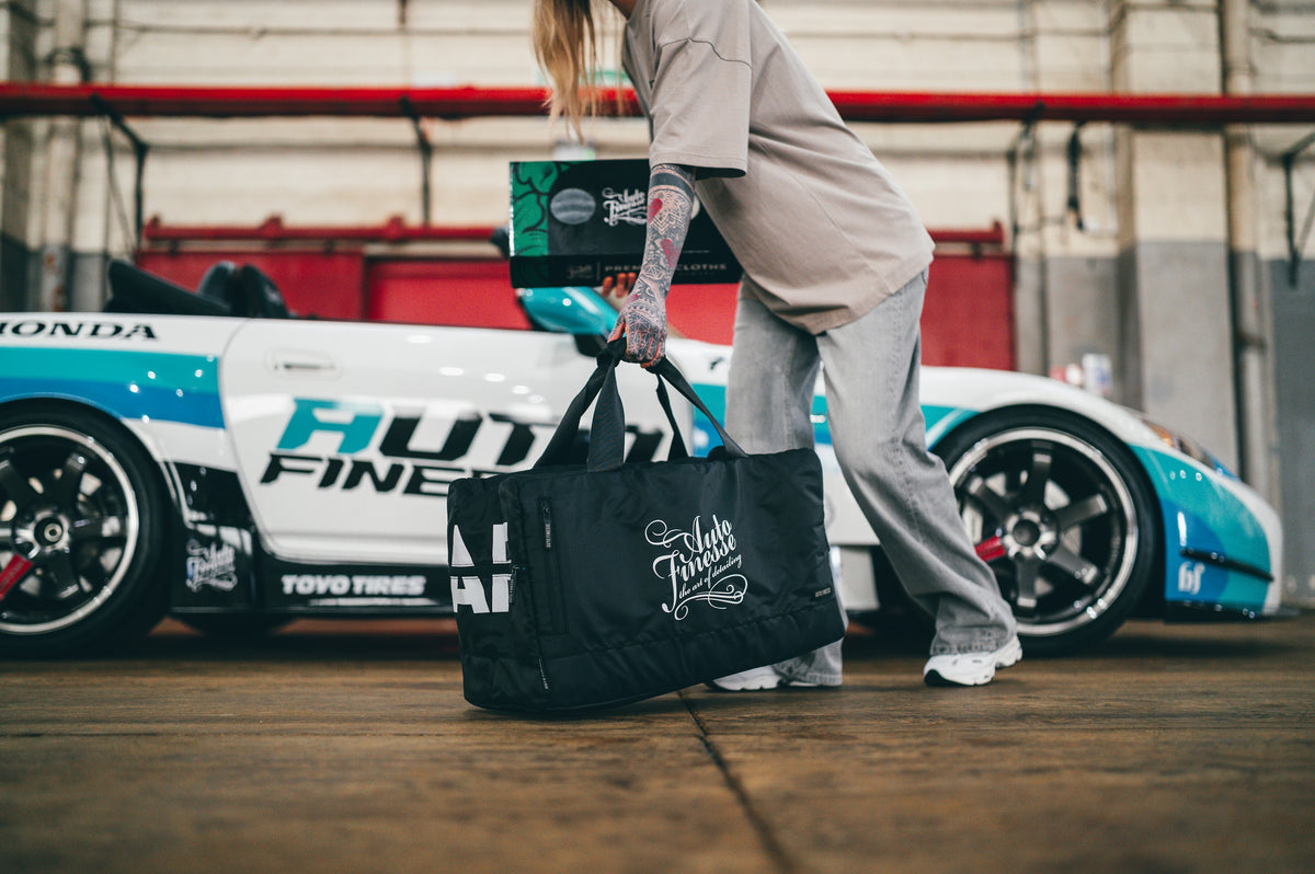 Woman carrying Auto Finesse bag with a car in the background