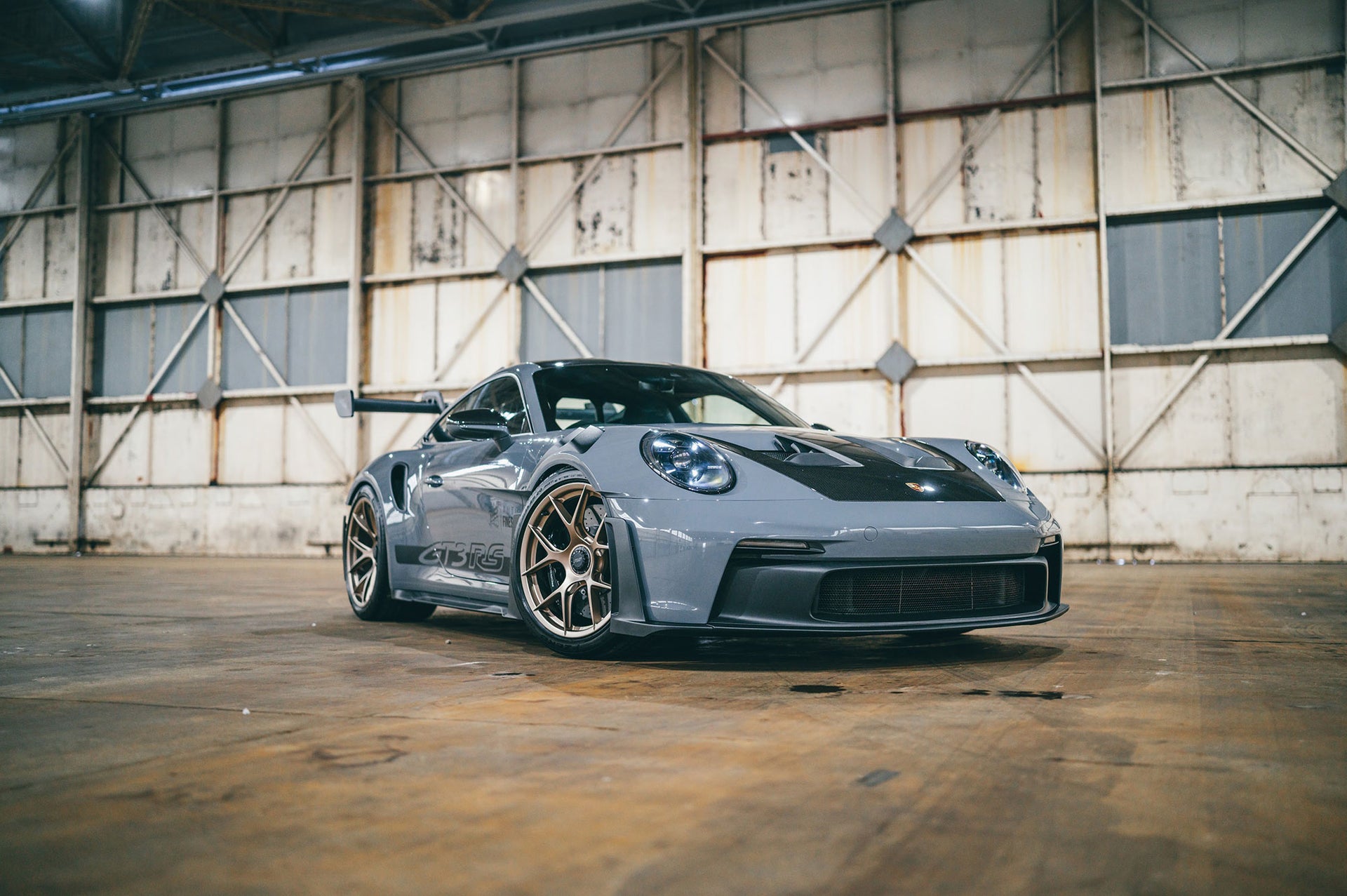 Gray sports car with gold rims in a warehouse setting