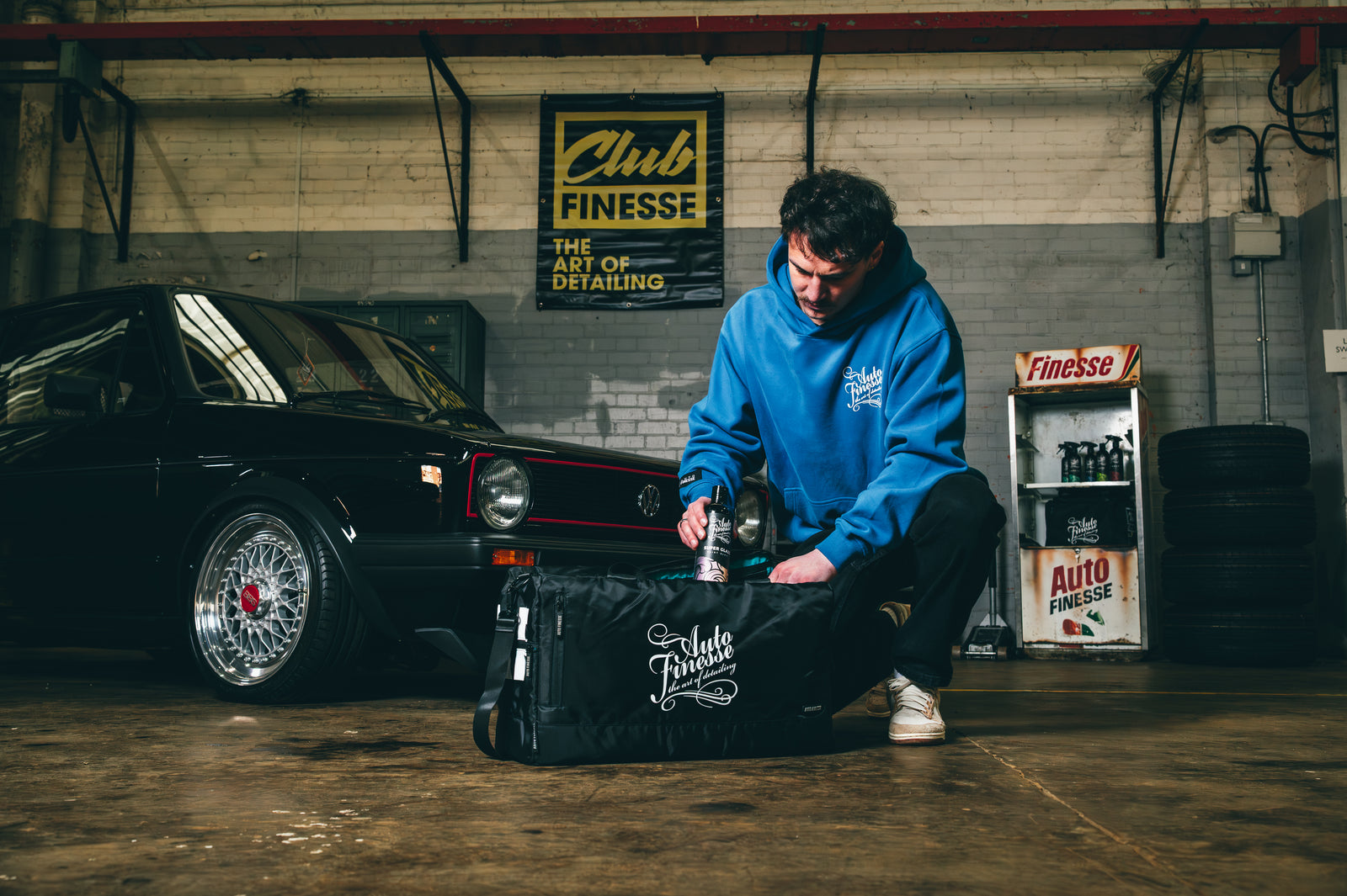 Man preparing a detailing kit near a black car in a garage