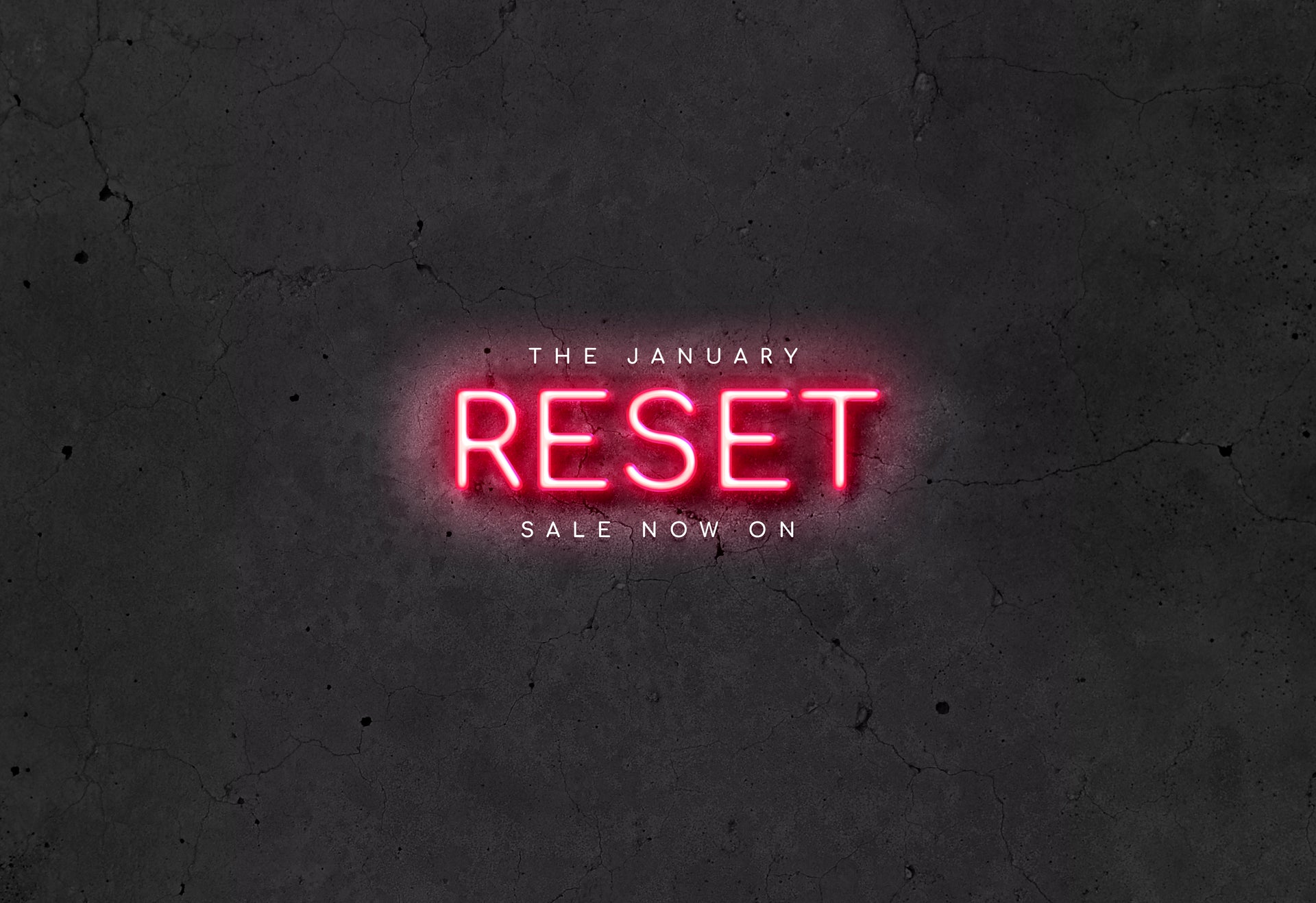 Neon sign with 'The January Reset Sale Now On' text on a dark textured background