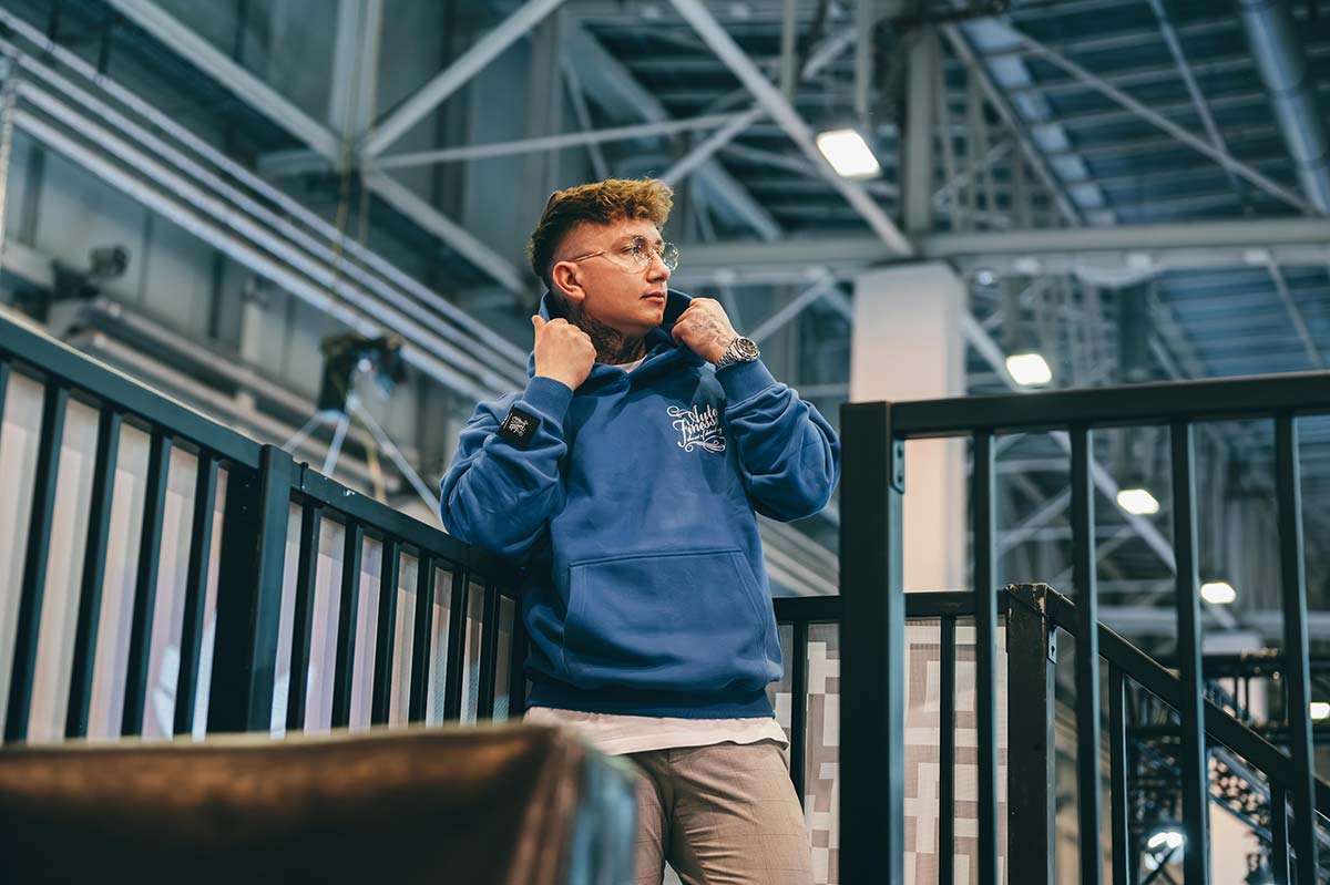 Man wearing a blue Auto Finesse signature hoodie posing inside