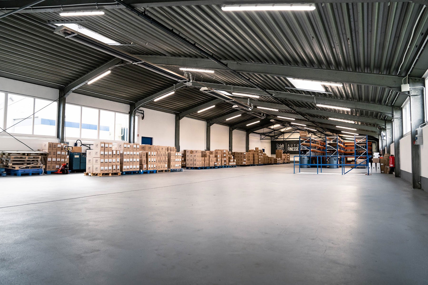 Large warehouse with stacked boxes and pallets under a metal roof.