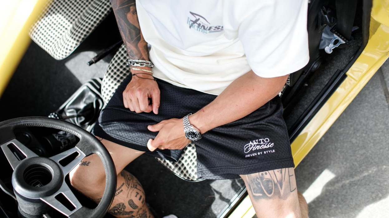 Person wearing black shorts with branding inside a car.