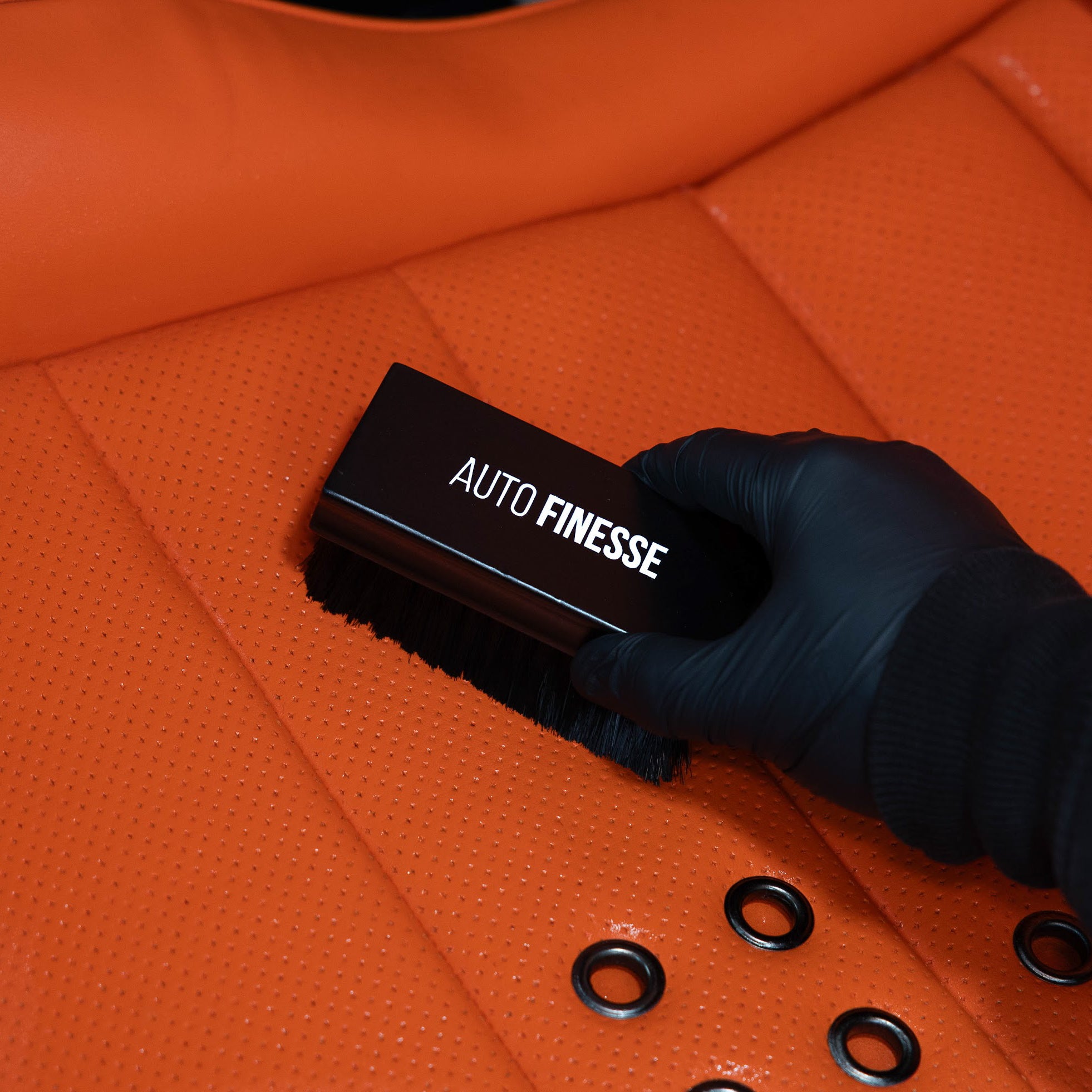 Brushing leather seat with Auto Finesse Upholstery brush_ Leather Cleaning Kit