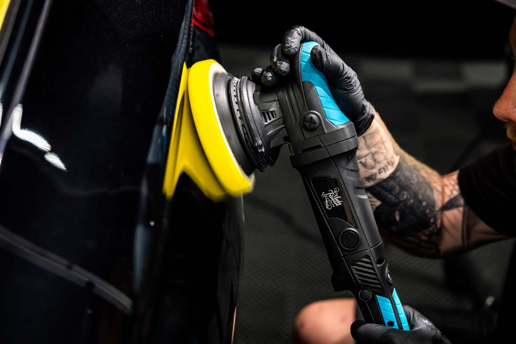 Detailer using dual action polisher on a black car