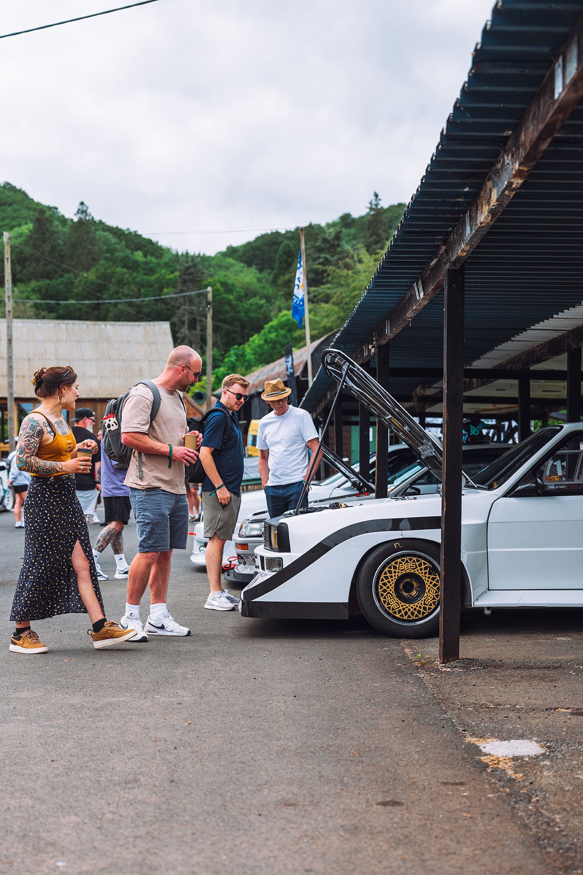 People inspecting white race cars under canopy
