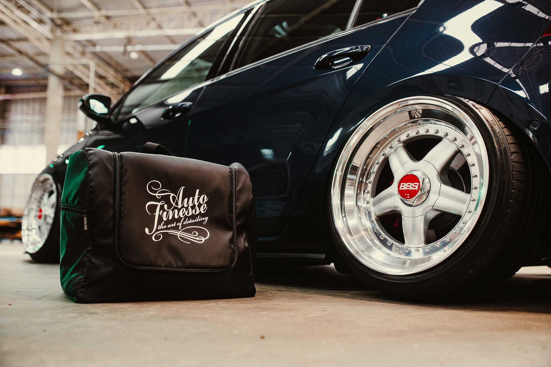 Car with a black bag featuring 'Auto Finesse' branding on a concrete floor.
