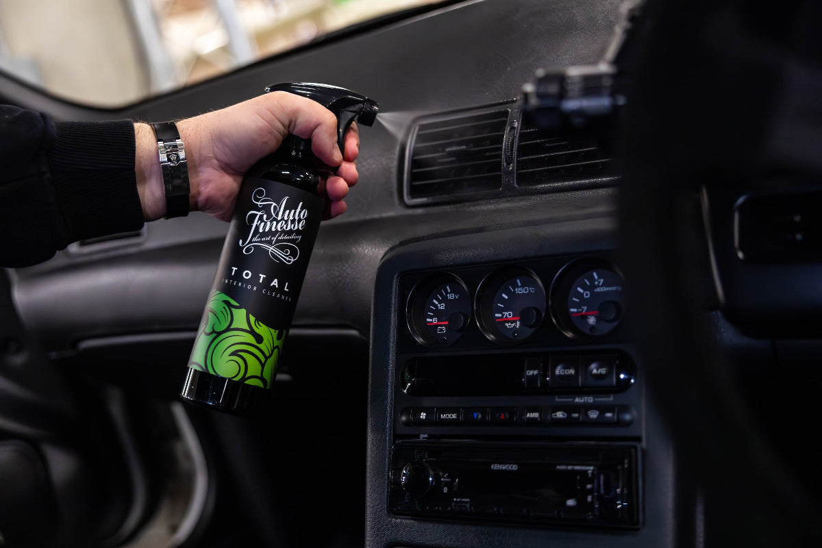 Person holding a car interior cleaning spray can in a vehicle.